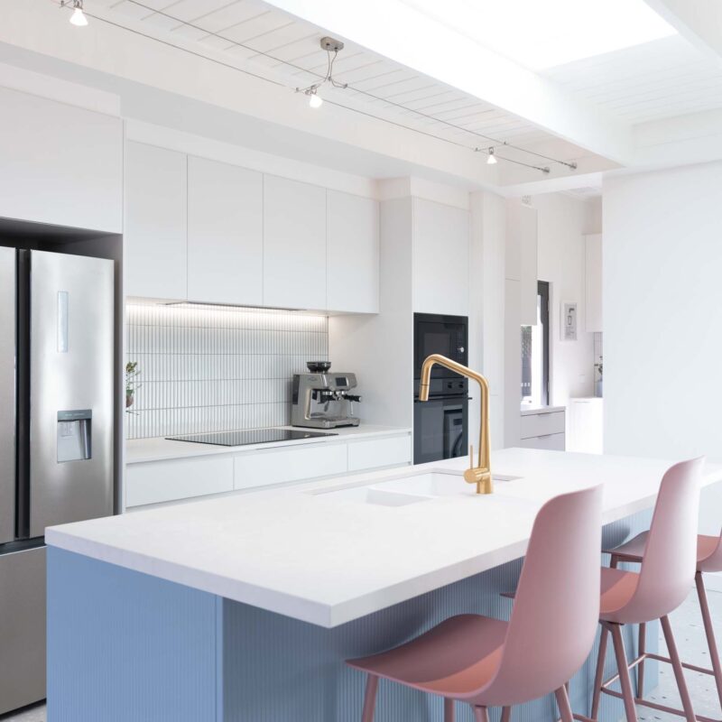 White Galley style kitchen with a Denim blue vertical striped island bench and pops of colour