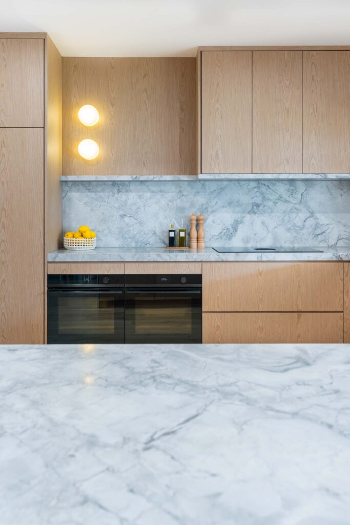 An Organic and delicate blond timber veneer, showcasing natural marble and high end Fisher and Paykel appliances.