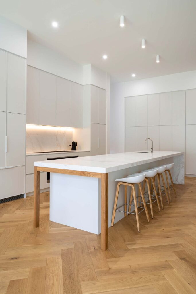 Modern Shaker kitchen with a Kiev 10 white grey profile. Timber features on the island and white hidden handles help define the space and offer warmth.