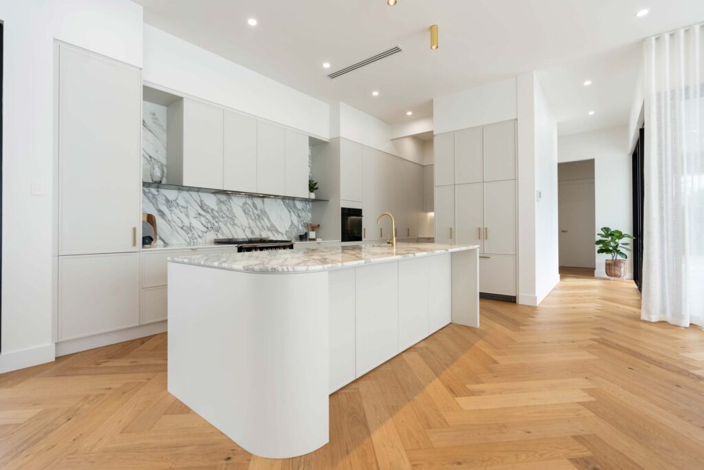 Herringbone blond flooring allows the marble feature of the splash back and benchtop to pop from the white grey Kiev 20 cabinetry.