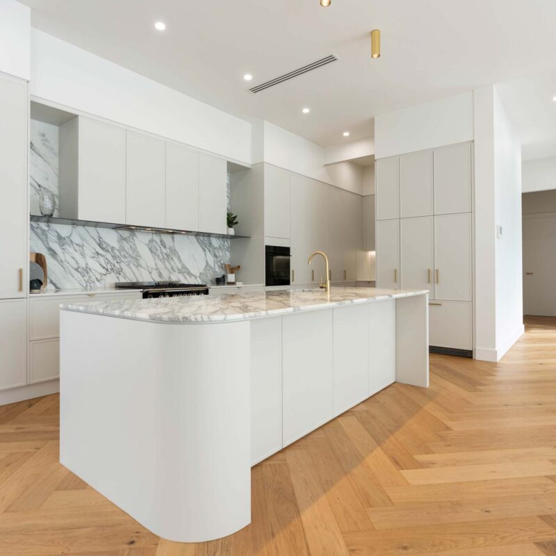 Herringbone blond flooring allows the marble feature of the splash back and benchtop to pop from the white grey Kiev 20 cabinetry.