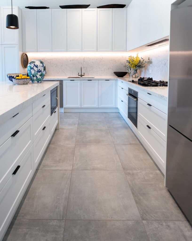 A Grey concrete look tile flooring enables the white form flow kitchen to sit proud, whilst the black features stand out with the artworks.