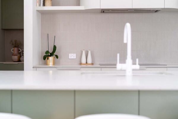 Kit kat tiles, green Bayleaf and white grey curved cabinetry with white sink, tap and lip handles.