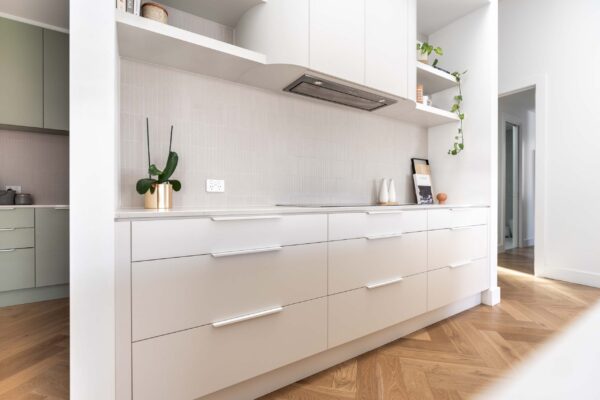 Subtle White and grey cabinetry with kit kat tiles and curved rangehood set in the background. Open shelving adds creativity.