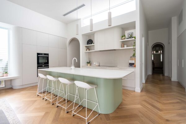 A fresh and open kitchen with subtle mid tones of green, grey and white all help create a defined kitchen space in the center of the home.