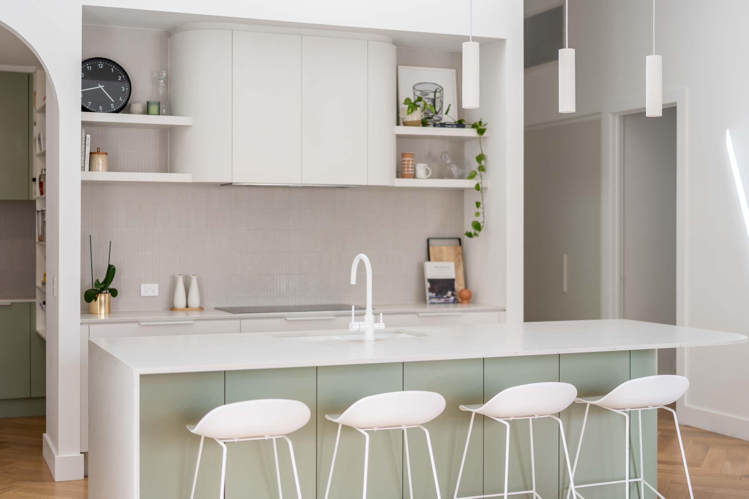 A fresh and open kitchen with subtle mid tones of green, grey and white all help create a defined kitchen space in the center of the home.