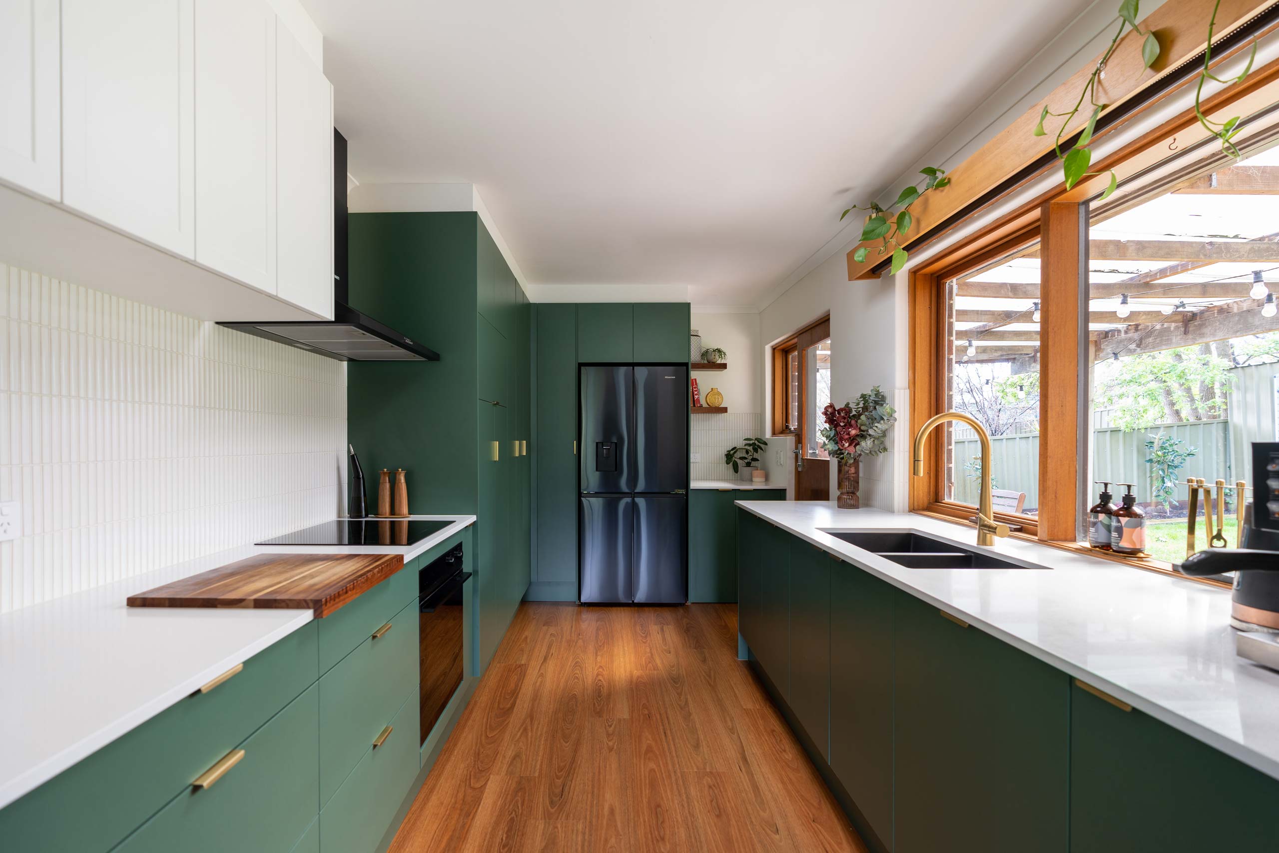 Hushed pine galley kitchen with white accents and brass hardware. Warm timber features add elegance and style.