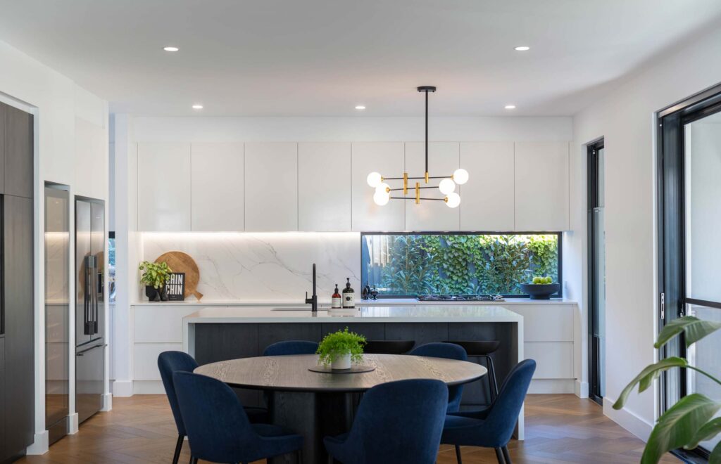 Clean lines of classic white cabinetry with contrasting dark woodgrain paneling. Open plan dining and kitchen space.