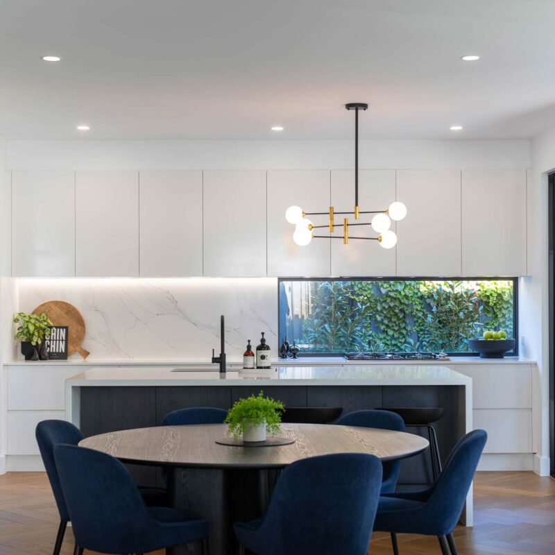 Clean lines of classic white cabinetry with contrasting dark woodgrain paneling. Open plan dining and kitchen space.