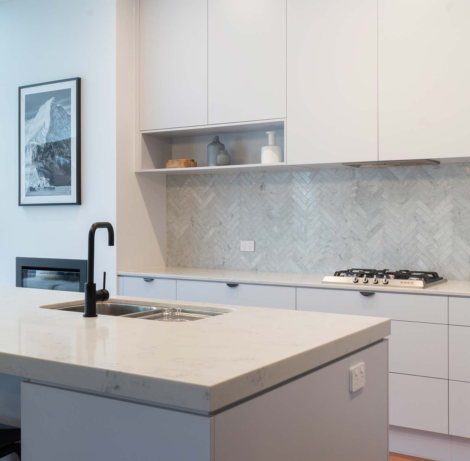 White and Grey Kitchen, with parquet tiled splashback in marble. Smeg cooktop, black tap with a stainless steel double bowl.