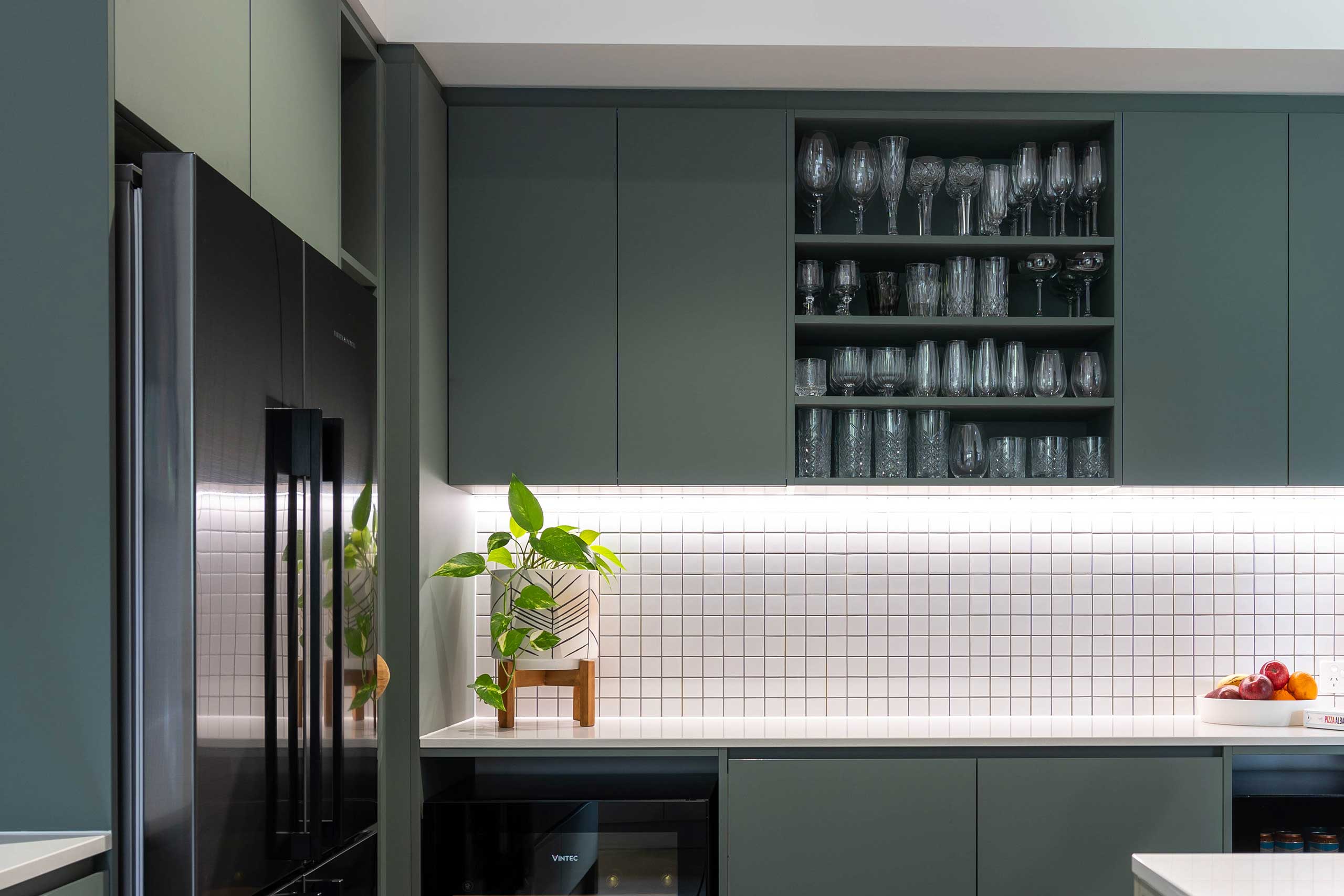 Slate green over heads with open shelving, paired with small white square tiles adding a natural feel.