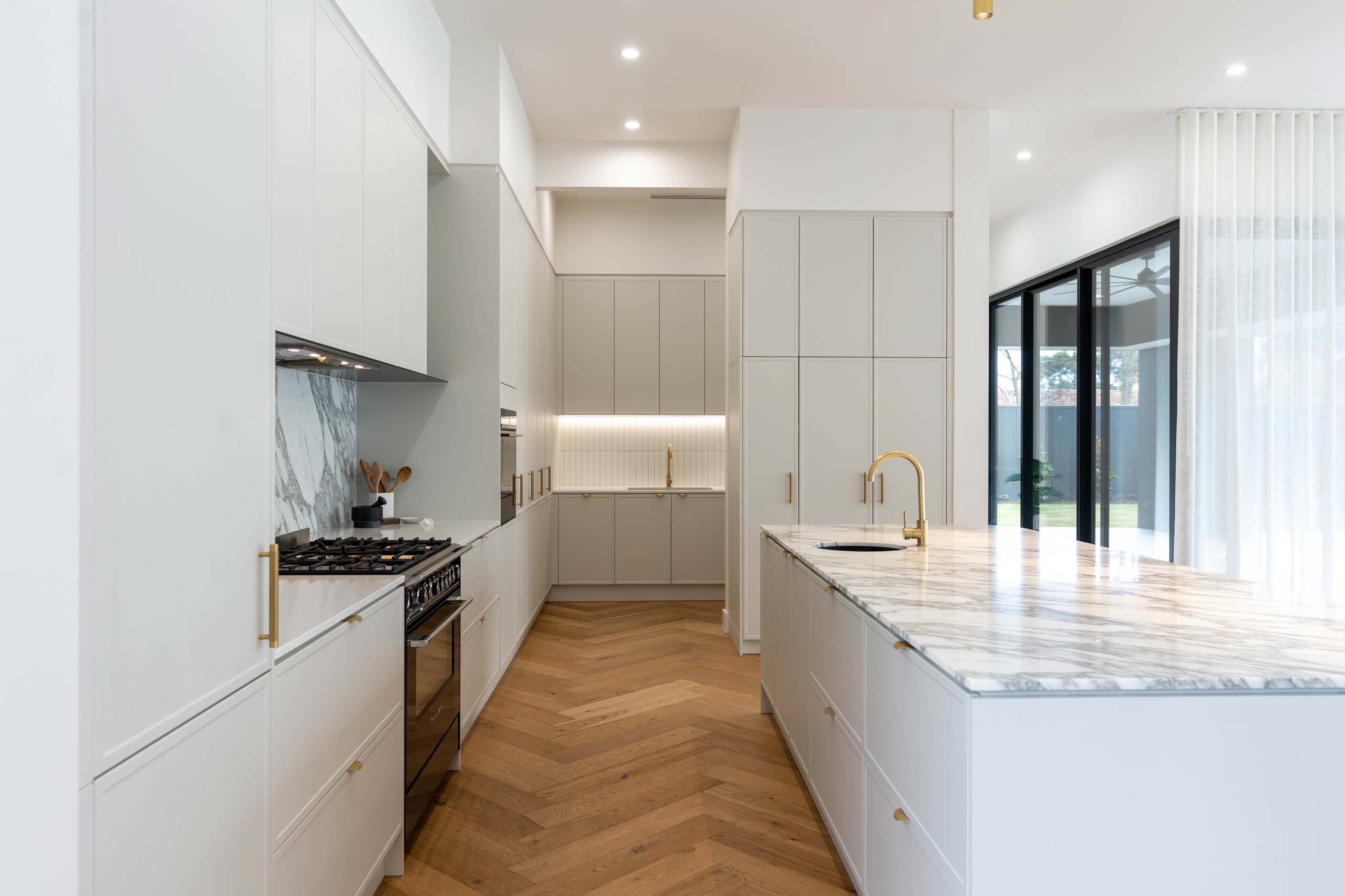 White grey form thermolaminated door profiles in Kiev 20. Gold lip pull handles and natural marble. Herringbone floor with butlers pantry.