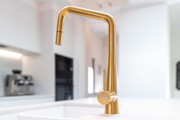 Gold oliveri tap on white stone with white sink