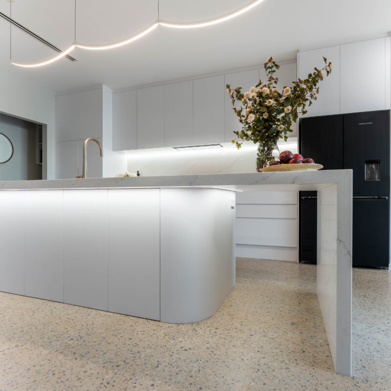 Kitchen. Classic White. Farquhar Alpine white with Zenith like Marbella benchtop and curved strip lighting and island under bench. Black quad door fridge