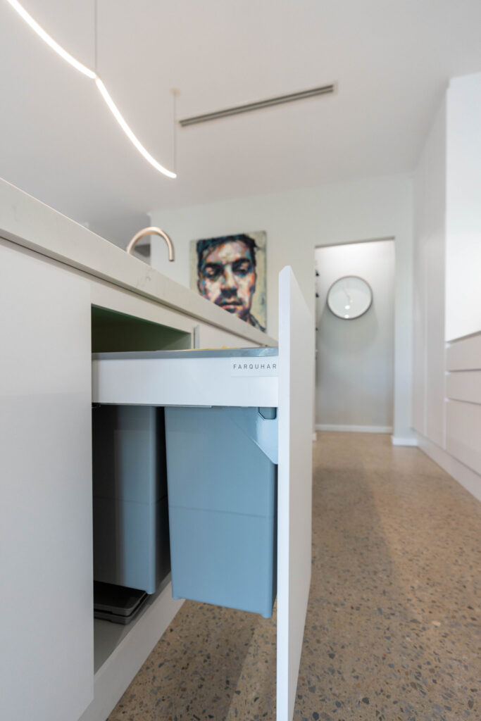 Kitchen with island bin draw pull out on polished concrete floor.