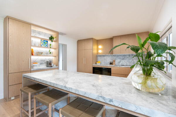 Kitchen. Delicately Organic. The detailed design of the stone on the shelving, bar back and waterfall end. Beautiful blond timber. Breakfast bar area.