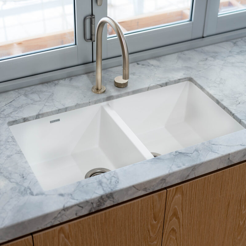 Kitchen delicately organic. Blond timber veneer, natural marble, white sink and silver tap.