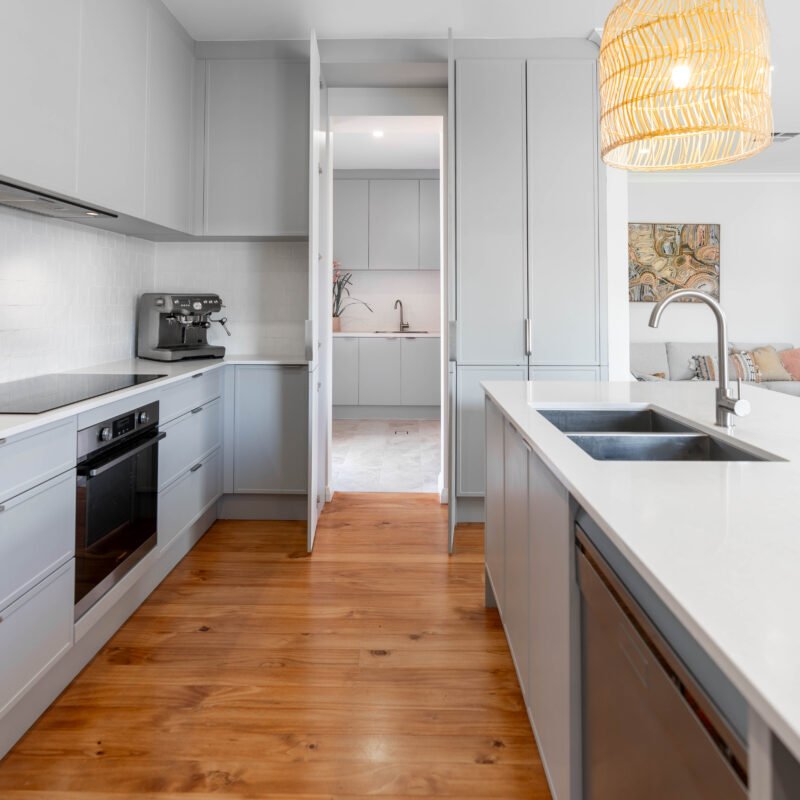 Kitchen in Farquhar Pearl grey Kiev profile. L shape light and natural. Fresh and coastal. with hidden walk in pantry and laundry.