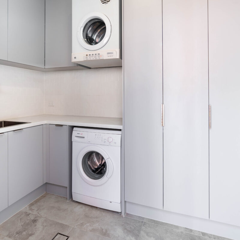 Laundry. Pearl Grey soft coastal Kiev 20 profile. L shaped. With large linen cabinets for storage.