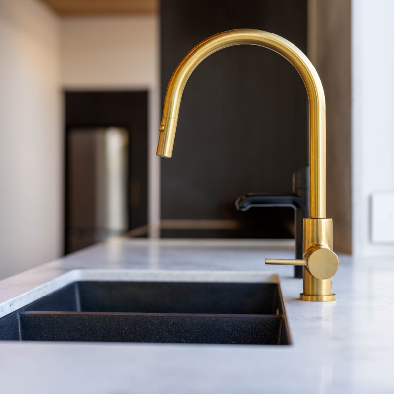 Gold brass Oliveri tap with black zip tap and sink.