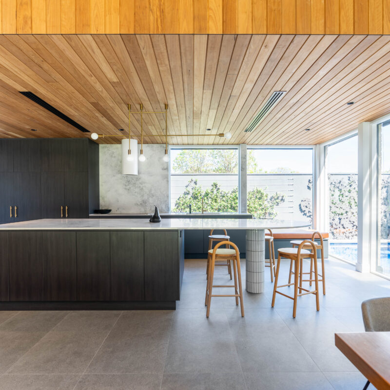 Benchtops run throughout, in an elegant marble inspired contrast of light and grey shades, and organic movement. The seating end of the benchtop features a kit kat tiled column support, adding further texture and detail, later reflected in the splashback of the butlers pantry. Functionality The use of integrated appliances, double ovens, a butler's pantry and second workspace provide amenity for food prep and clean up, and a long and wide island bench is perfect for the family to enjoy casual meals and entertaining. Contrast Laundry The laundry and mudroom is large and practical, without skimping on style. Warm classic oak and indigo blue cabinetry creates a light and dark contrast, complemented by gold hardware and balanced with cool grey benchtops and tiling.