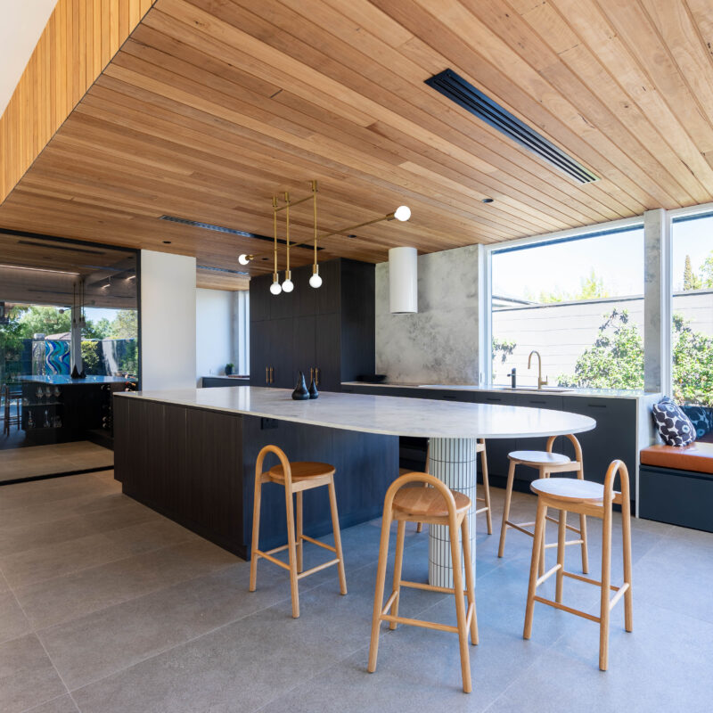 Kitchen, open plan, timber ceiling and dark wood like cabinetry, with curved bench. Window bench seating