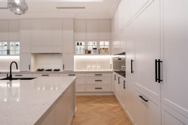 Hamptons Glamour. Classic shaker-style cabinetry and touches of modern glamour. The pearlescent finish of the cabinets in ghost gum satin swathes the space with the feel of luxury. The bold, black metal accents add a modern edge to the design.