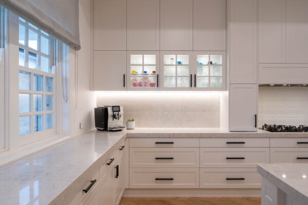 Hamptons Glamour. Classic shaker-style cabinetry and touches of modern glamour. The pearlescent finish of the cabinets in ghost gum satin swathes the space with the feel of luxury. The bold, black metal accents add a modern edge to the design.