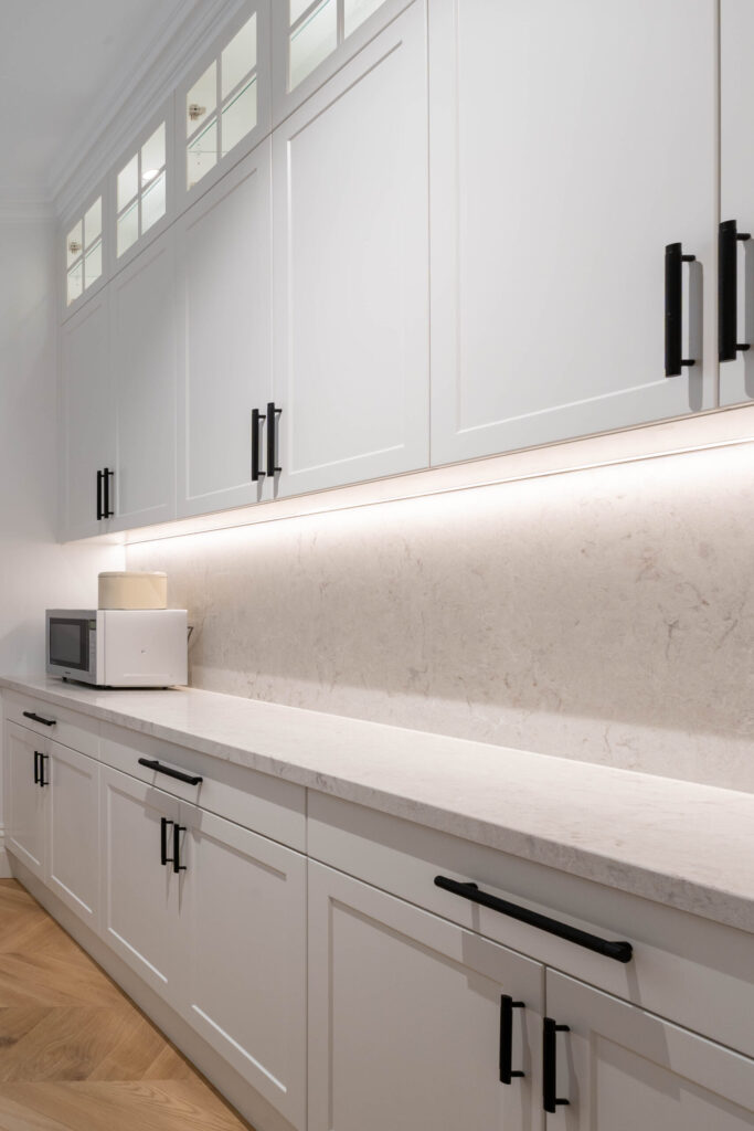 Walk in Butlers pantry with Barossa white cabinetry, black handles and glass inserts.