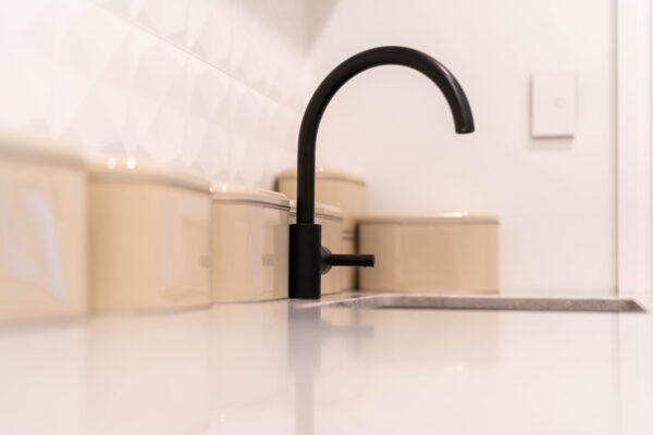 Black tap and sink on stone benchtop