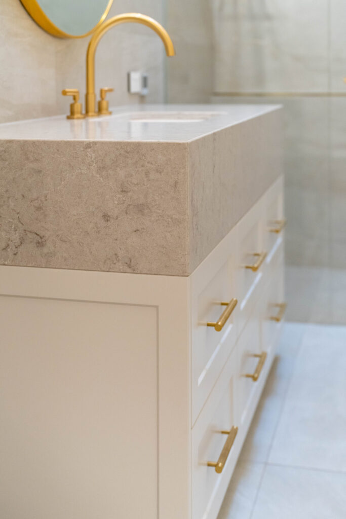 Golden Vanity with white pearlescent cabinetry and warm stone.