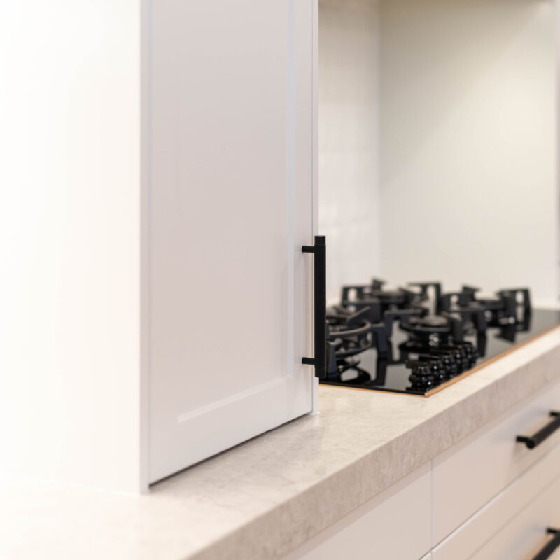 The pearlescent finish of the cabinets in ghostgum satin swathes the space with the feel of luxury. The bold, black metal accents add a modern edge to the design.