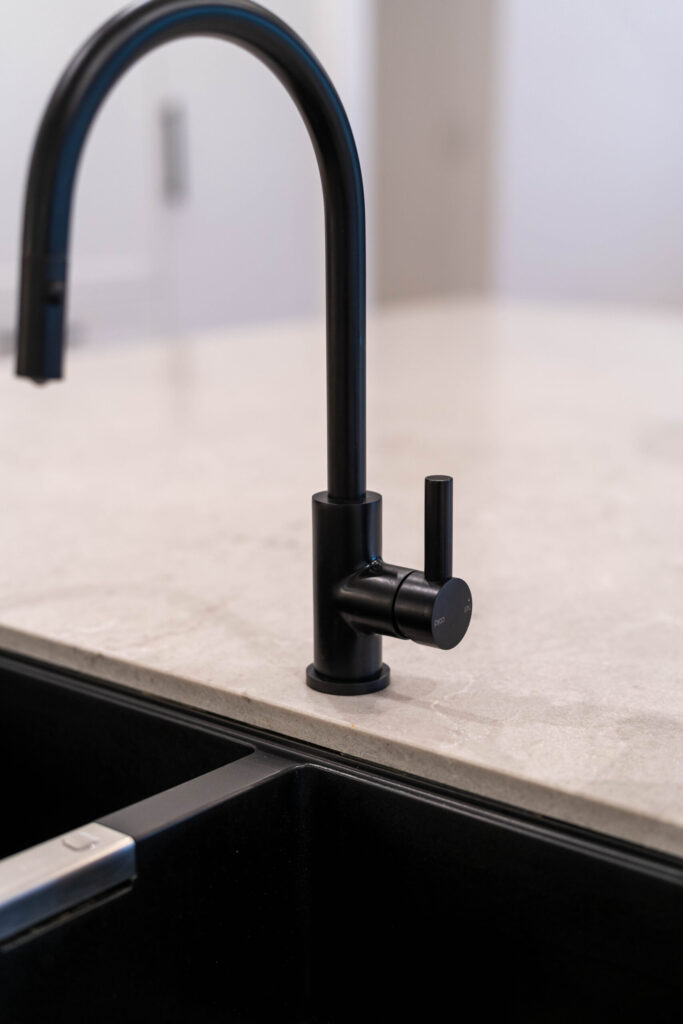 Black Oliveri sink and tap within a warm stone benchtop,