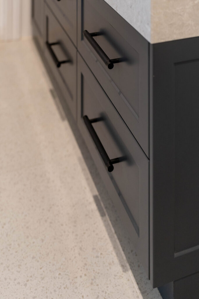 Bathroom Vanity. Barossa profile in a nice Graphite colour with deep warm stone like benchtop and black handles with soft tiles.