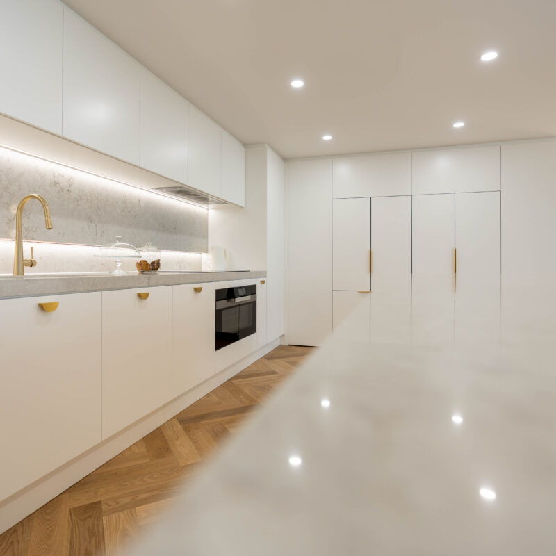 Illuminated Elegance Kitchen space. Open plan with herringbone light timber floors and curves. Premium white satin cabinetry with illuminated highlights.