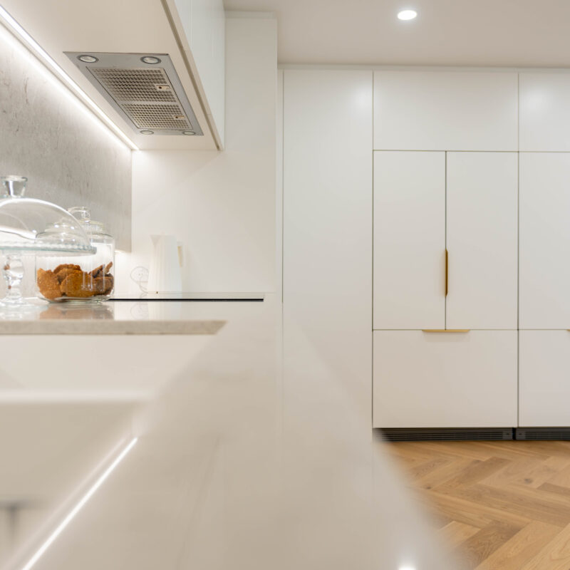Integrated fridges behind the Farquhar Satin premium white cabinets with gold handles.