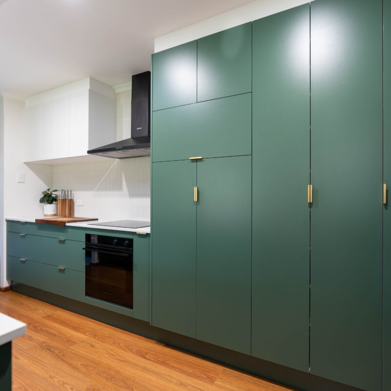 The bold Laminex Hushed Pine cabinetry makes a statement, paired harmoniously with earthy timber elements and the warmth of gold hardware. Softening and neutralising the palette is a small run of overhead cabinets in Farquhar’s Premium White in Barossa profile, and a swathe of kitkat tiles across the splashback.