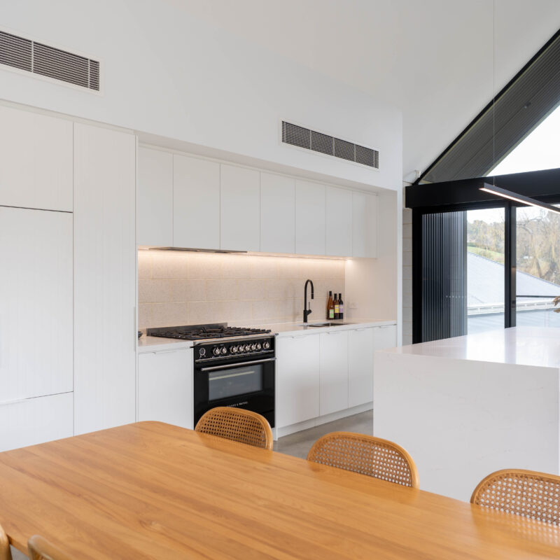 Black A line framed windows. Kitchen with Black Fisher and Paykel freestanding oven and cooktop with black tap create a bold contrast with the run of white profile cabinetry and beautiful timber dining table.