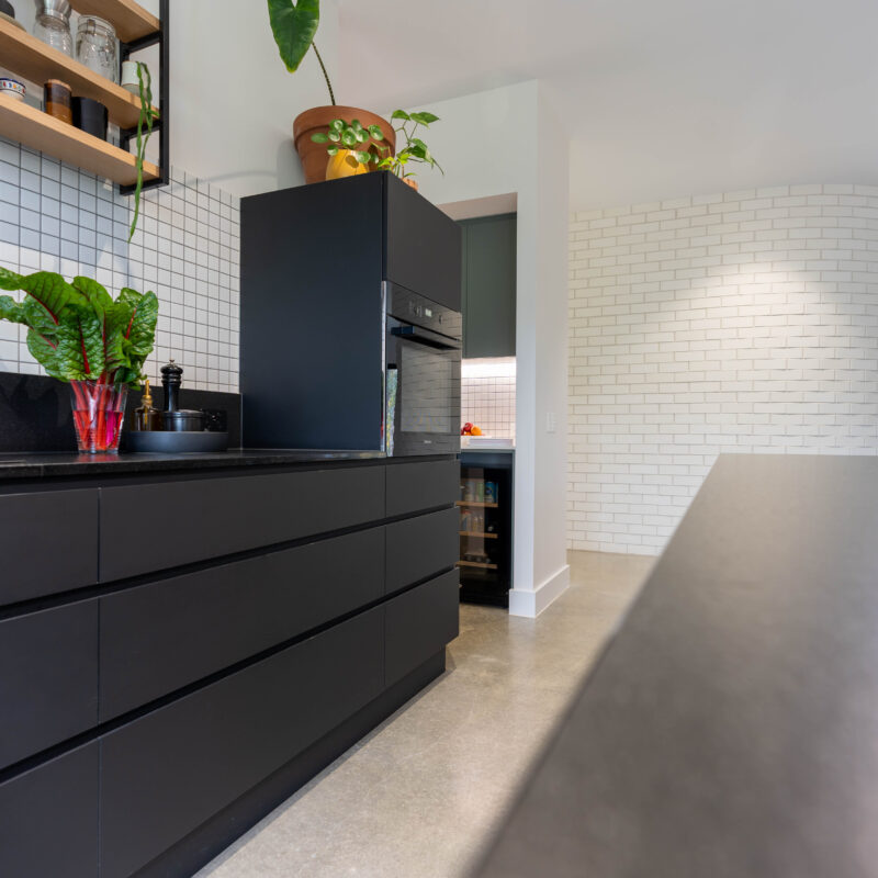 White curved brick wall with black and green cabinetry in the adjacent kitchen space.