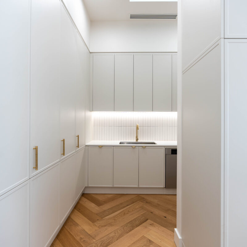 Walk in Pantry with thin subway tiles and white grey storage, clean lines and timber floors.