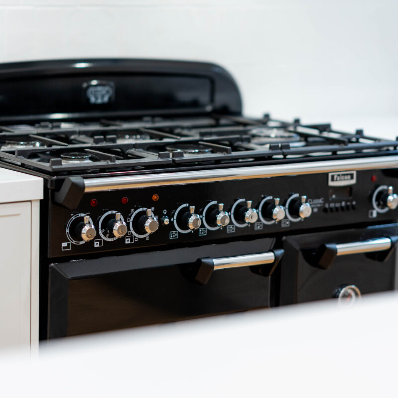 Black freestanding cooker with Farquhar Kiev Profile 20 white grey draw units with tradtional bronze handles.