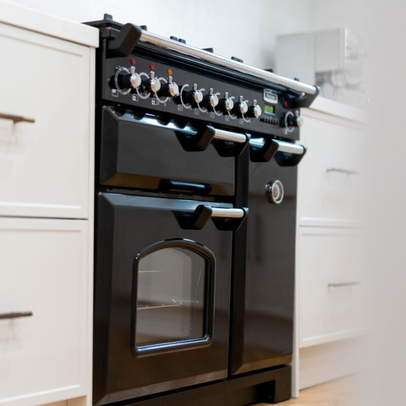 Black freestanding cooker with Farquhar Kiev Profile 20 white grey draw units with tradtional bronze handles.