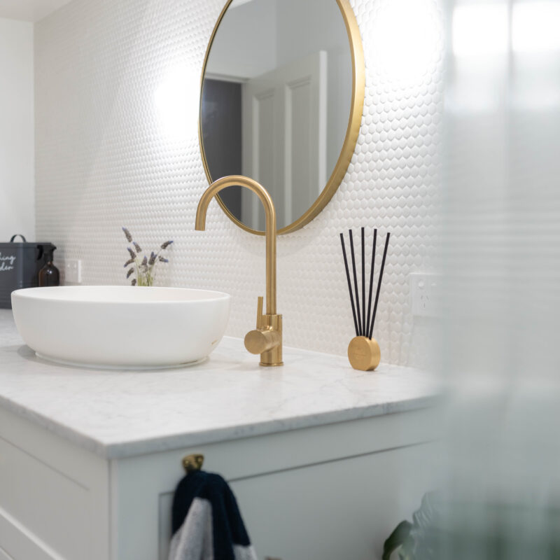 Bathroom Vanity Gold accents, with Zenith like benchtop and top mount white porcelain bowl. small rounded tiles and gold mirror