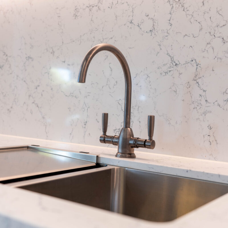 Tradtional tapware and organic grey tone stone. Stainless double bowl steel sink.