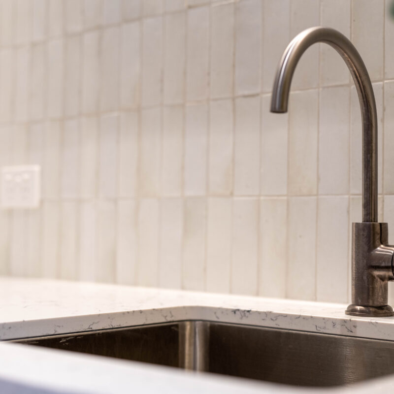 Laundry galley space. Crisp white cabinetry with grey tones and graphite hardware. elegant tiles.