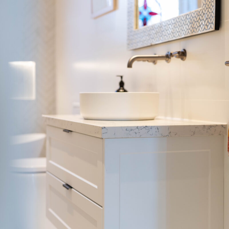 White Barossa profile cabinetry with 2 draws and round bowl with traditional tapware and grey tone benchtop in the style of zenith Carrara mist.