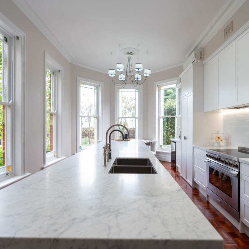 Entertainer's Delight The core kitchen space is balanced and mirror image. Extending down towards the windows, the kitchen transforms into an entertaining space; with a glass door cabinet, wine fridge, and space for four stools, mimicking a traditional table setting, with two either side.