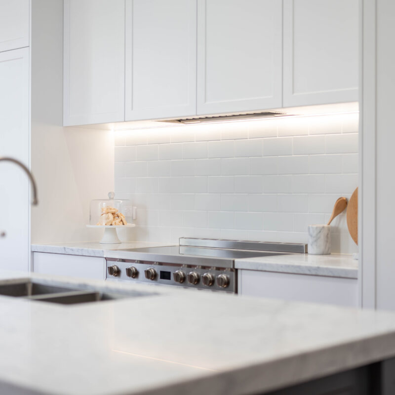 Entertainer's Delight The core kitchen space is balanced and mirror image. Extending down towards the windows, the kitchen transforms into an entertaining space; with a glass door cabinet, wine fridge, and space for four stools, mimicking a traditional table setting, with two either side.