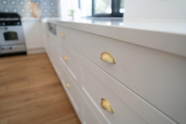 Farquhar Barossa style cabinetry draw banks with white stone and gold cup handles with a timber floor.