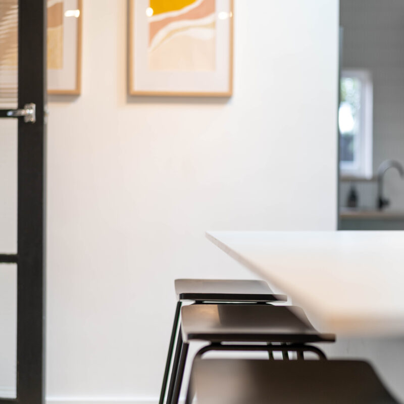 Black stools in island bar with white stone top